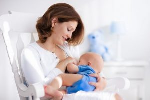 Young mother holding her newborn child breastfeeding